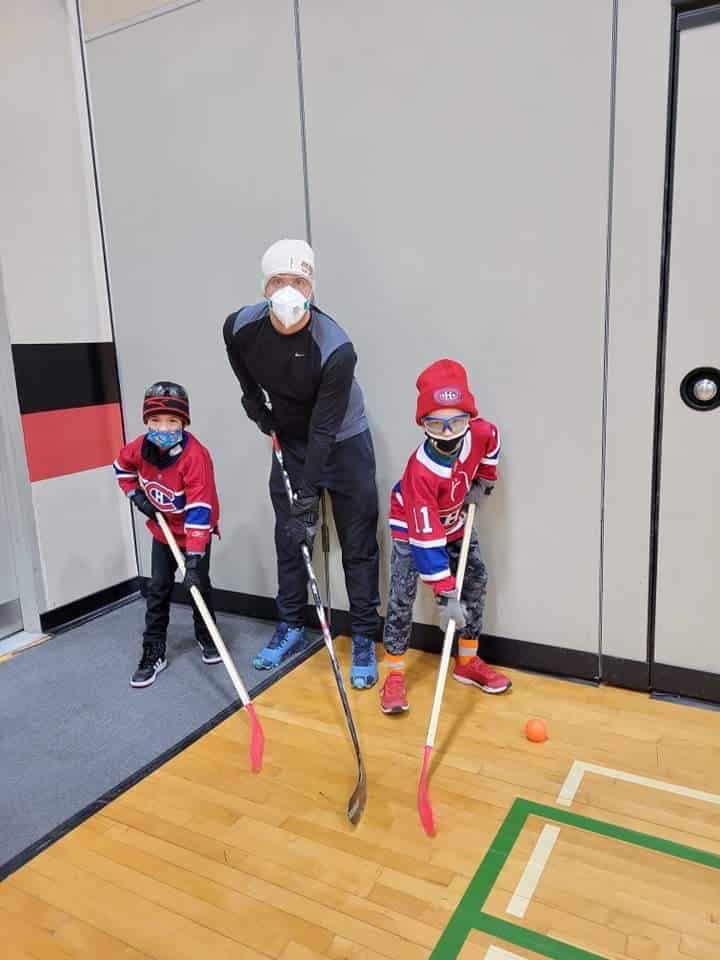 deux enfants et un adulte jouent au hockey